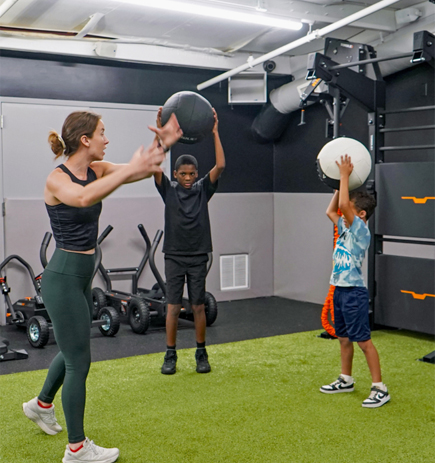 a trainer and boys holding balls at dedham health